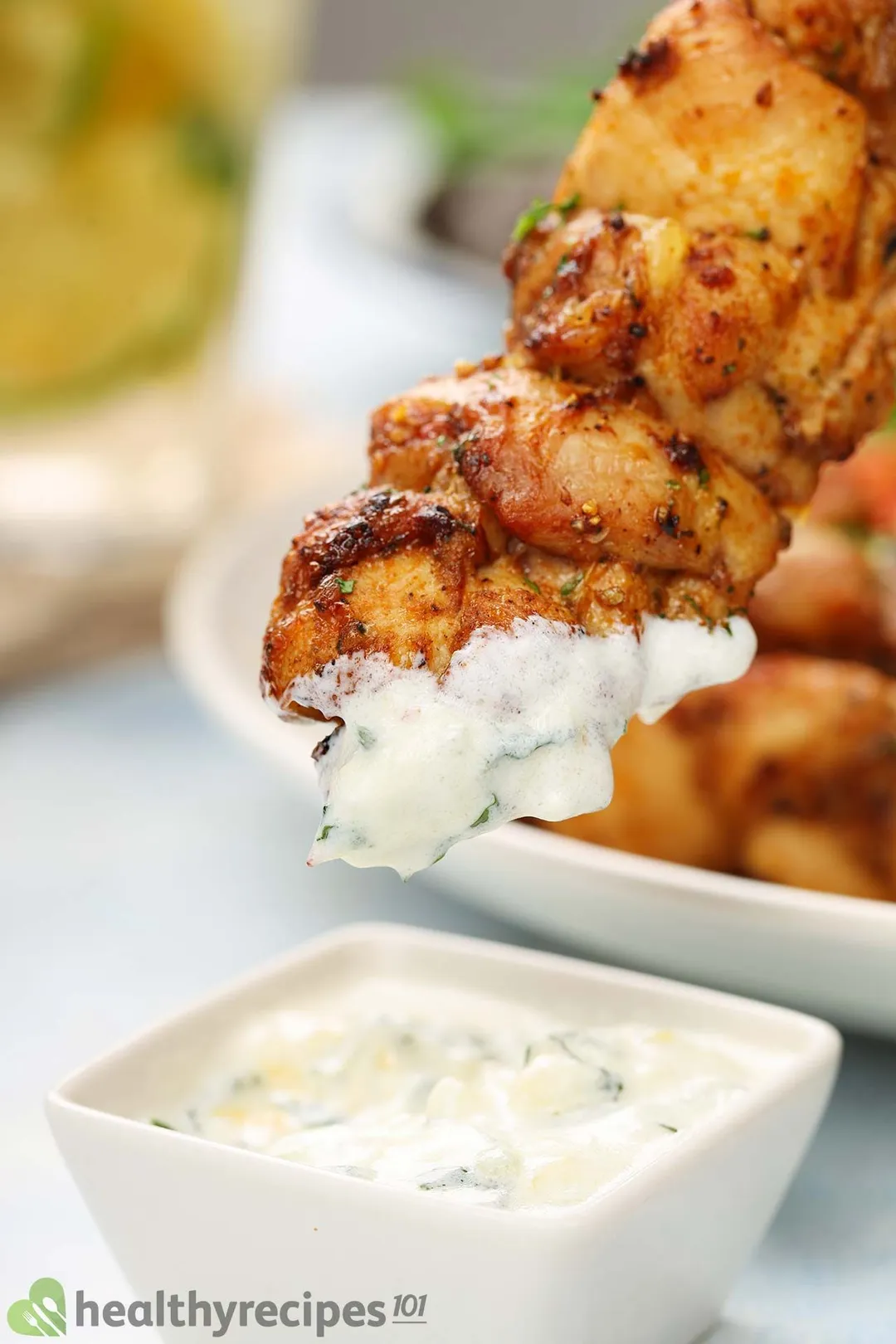 dipping cooked chicken skewer with sauce