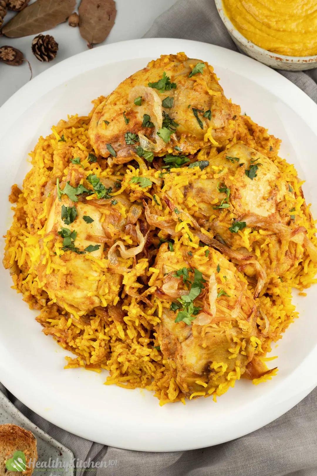a white plate of cooked chicken biryani with rice