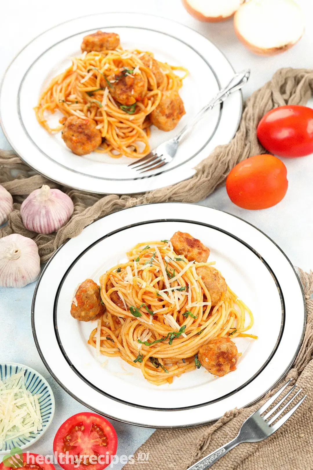 Two plates of chicken meatballs with spaghetti decorated with utensils