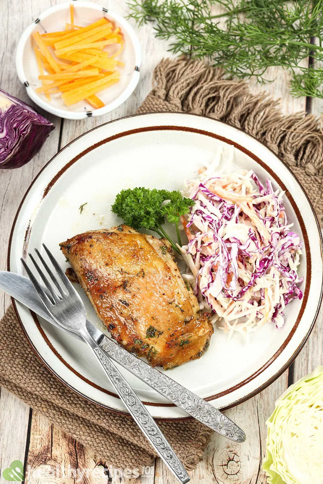 top view of a cooked ranch chicken thigh on a plate with shredded cabbage salad
