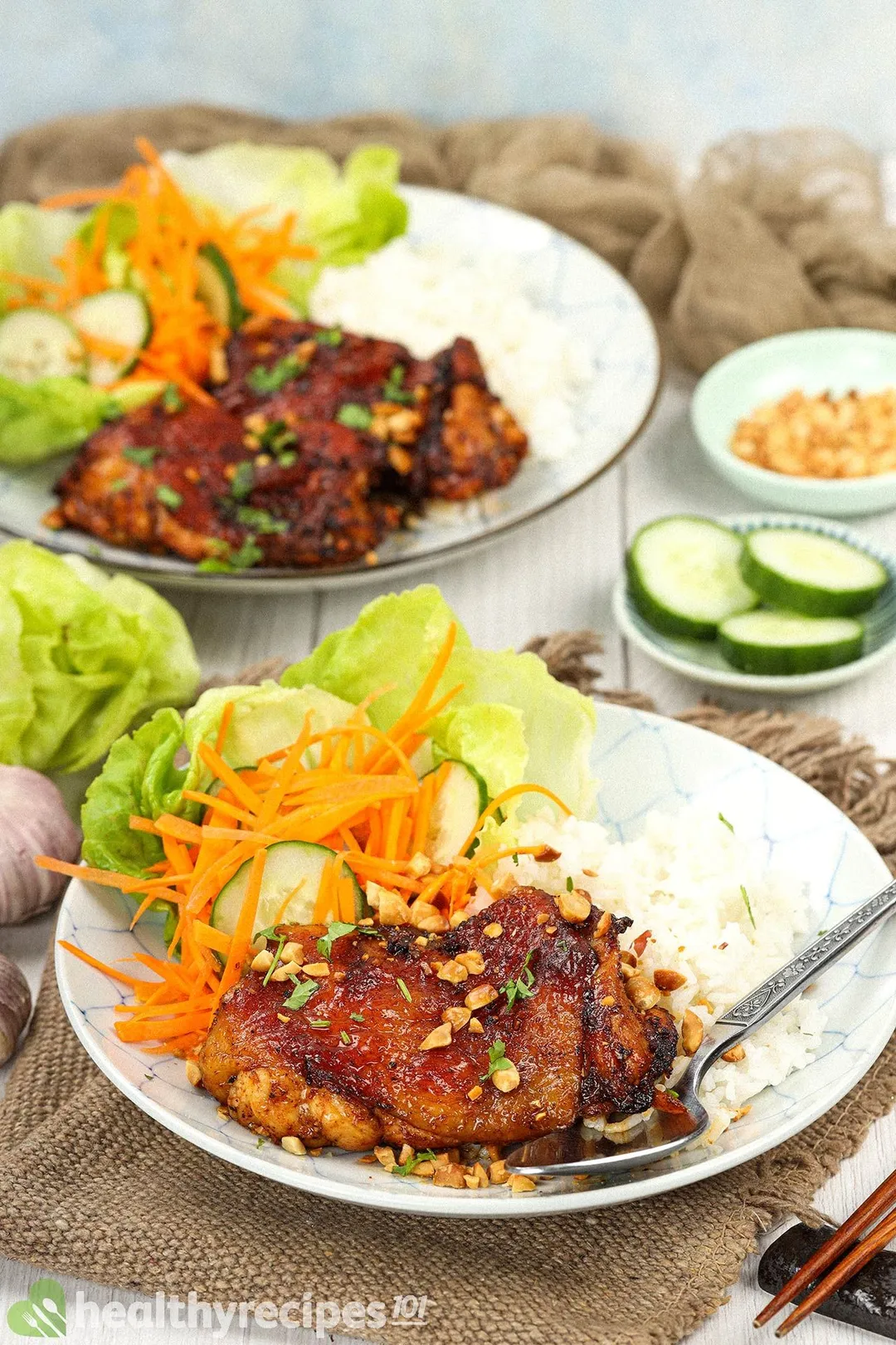 Two plates of Thai chicken decorated with utensils and a tablecloth