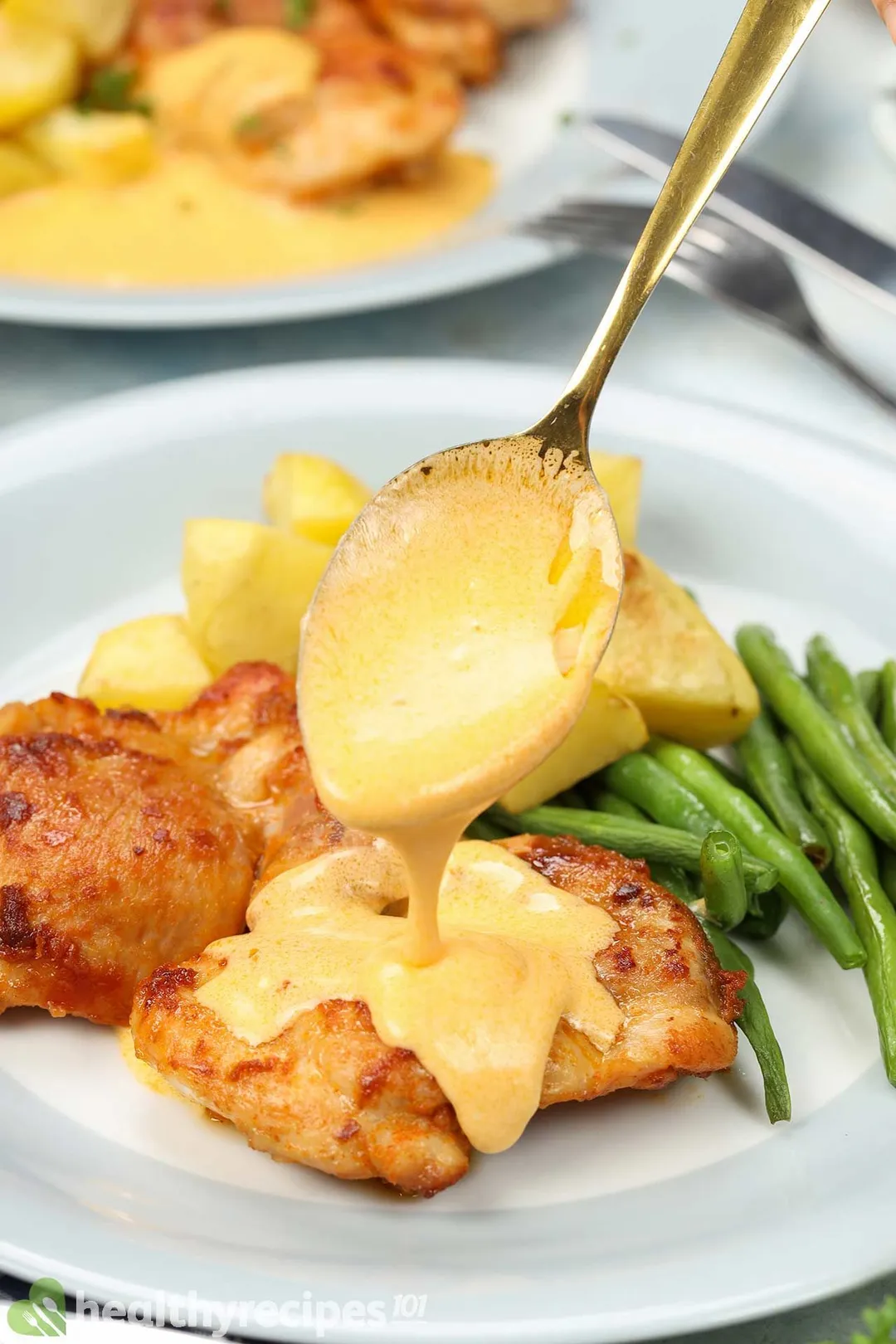 a spoon pouring sauce onto cooked chicken thigh