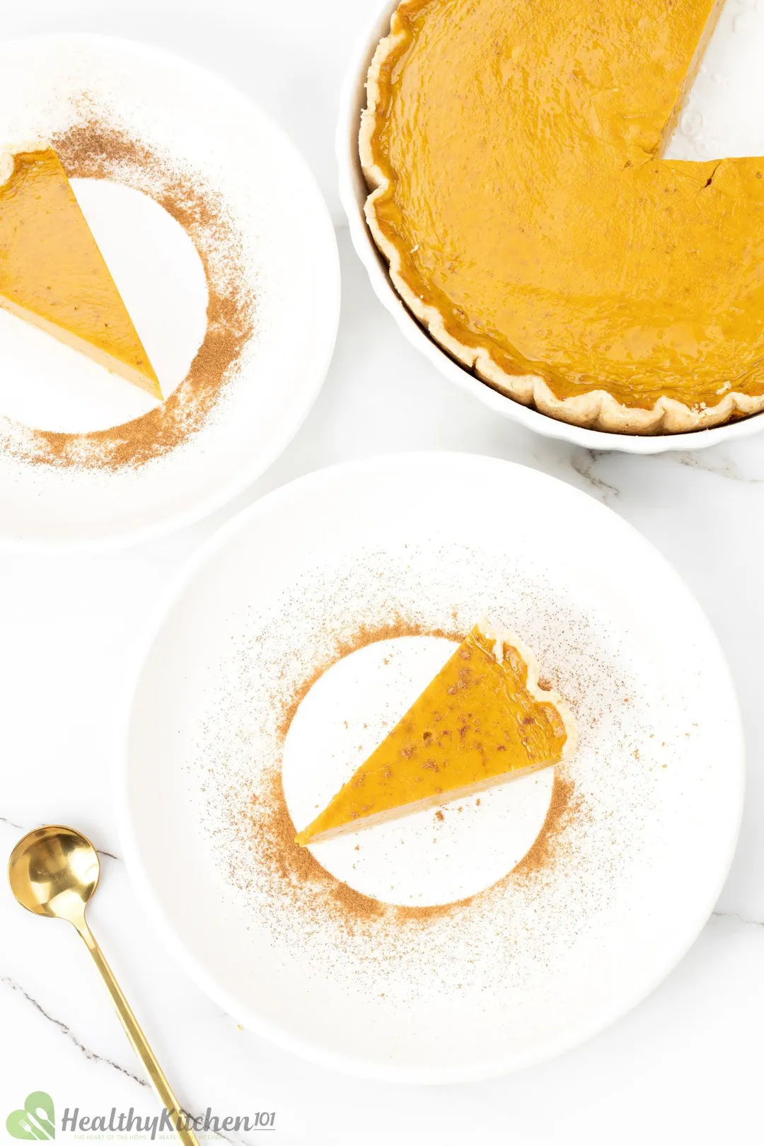 A high-angle shot of a pumpkin with two triangle pieces and a spoon nearby.