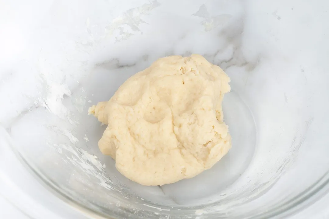 A large glass bowl with mixed flour in the center.