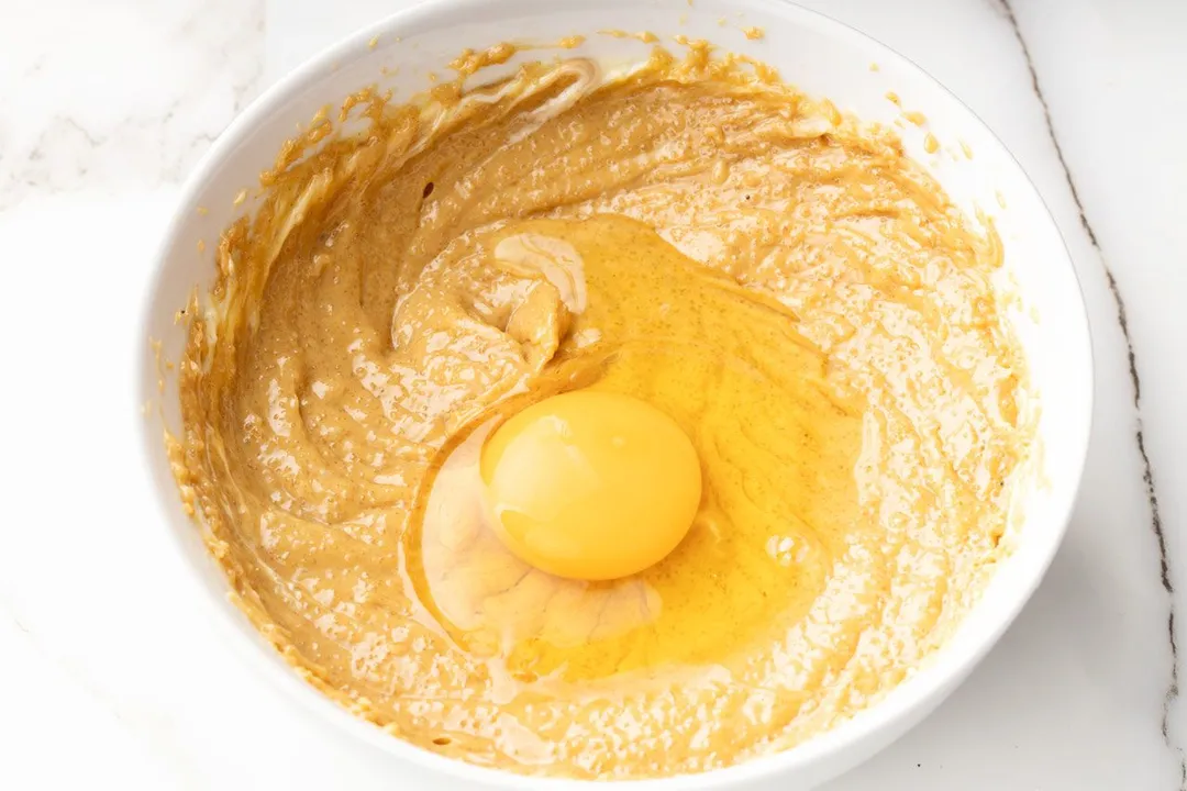 a beaten egg in a bowl of mixed peanut butter