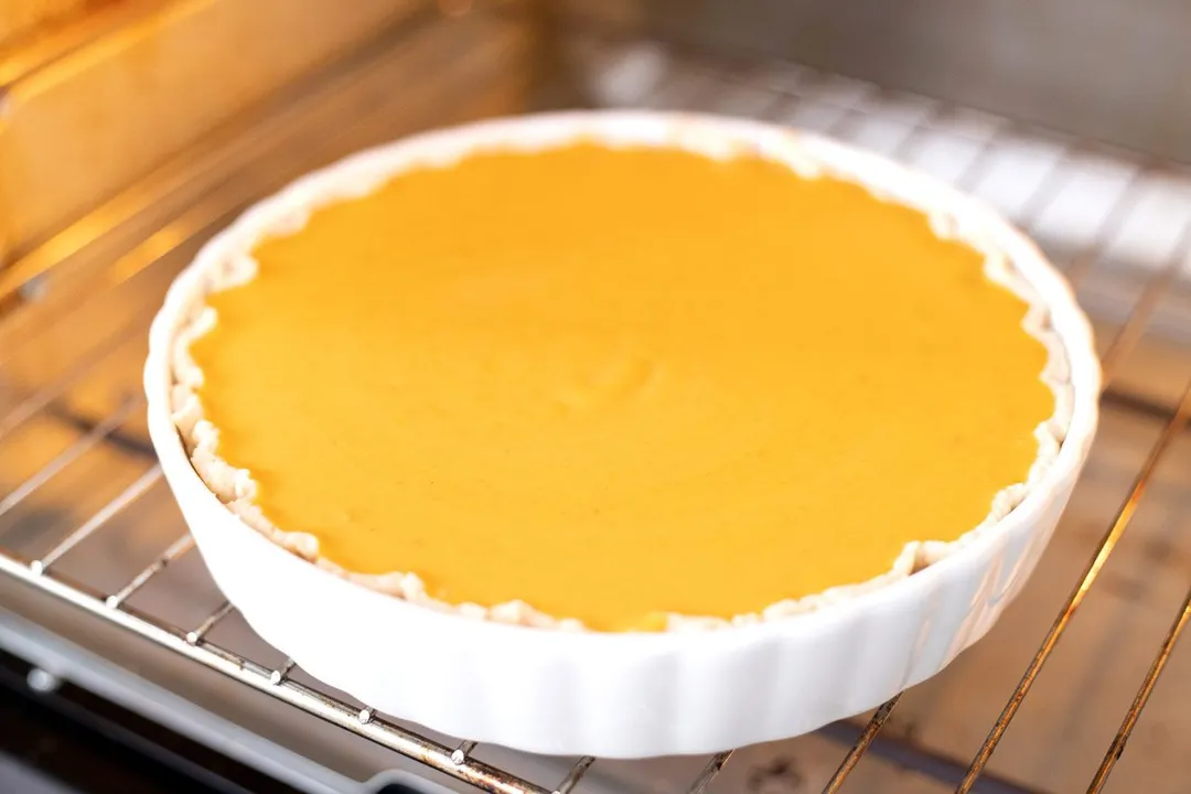 A pumpkin pie baking in the oven.