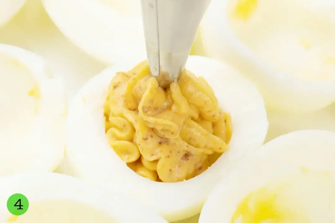 A deviled egg filling piped into half a boiled egg white