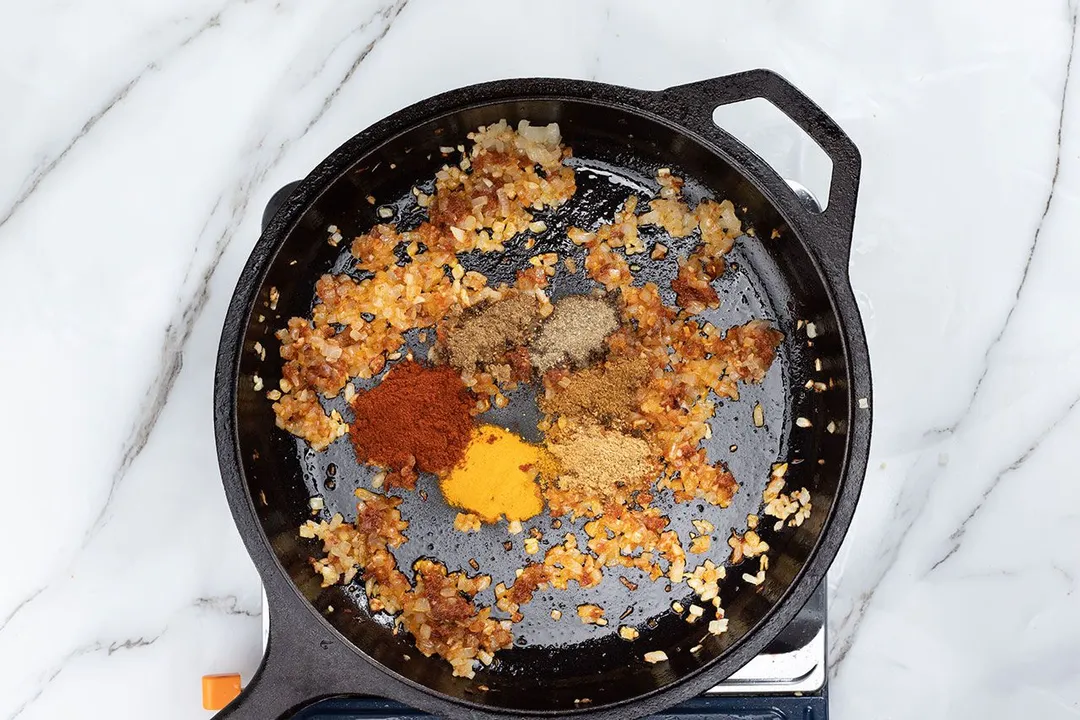 cooking curry paste with onion and seasoning in a skillet