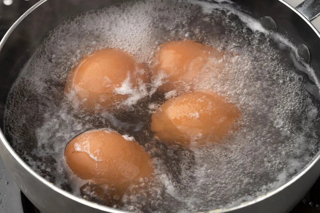 four eggs boiling in a pot