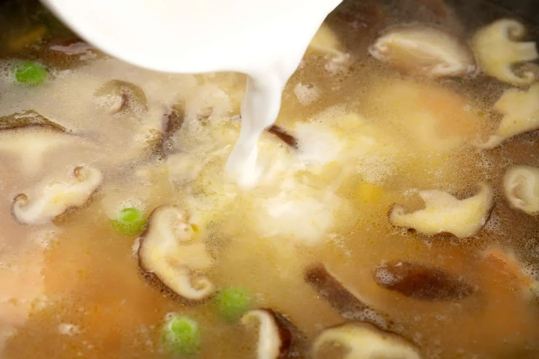 pouring white liquid into soup