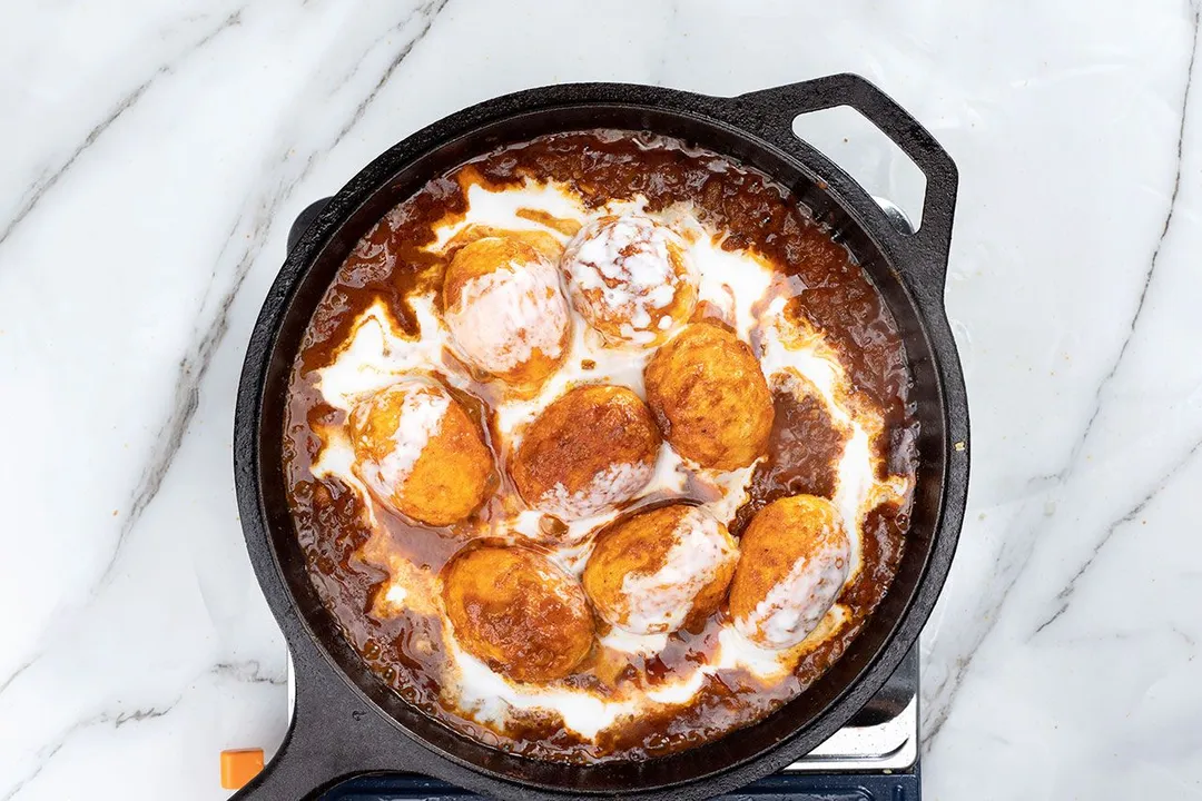 cooking eggs with coconut milk and curry in a cast iron skillet