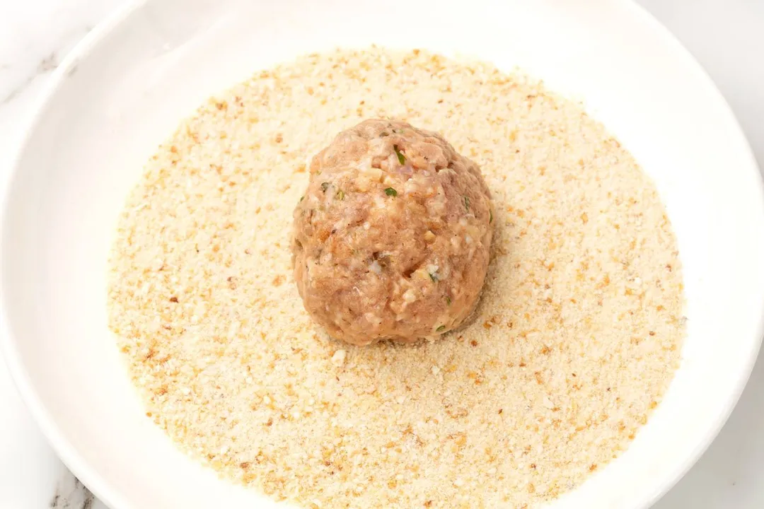 a meatball on a plate of breadcrumbs