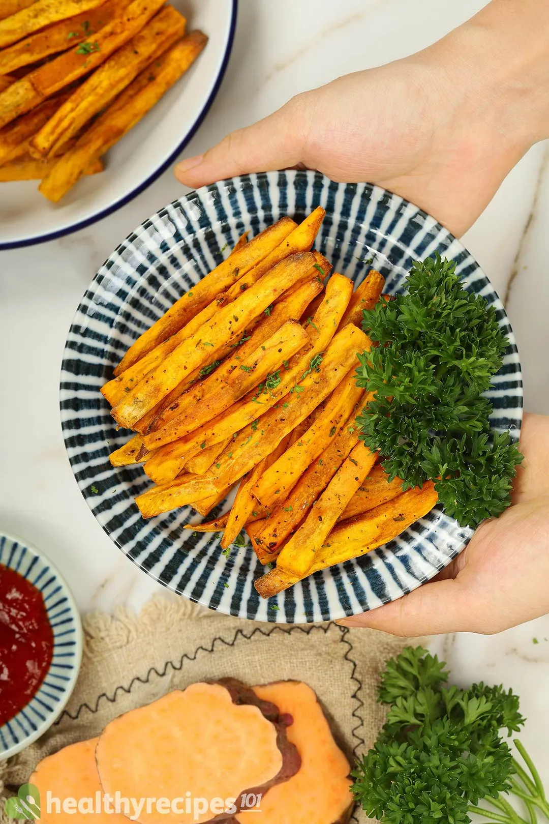 two hands holds a plate of sweet potato sticks