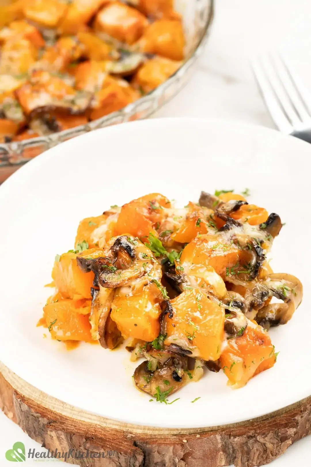 A plate of glossy butternut squash casserole with sliced button mushrooms presented in a white plate