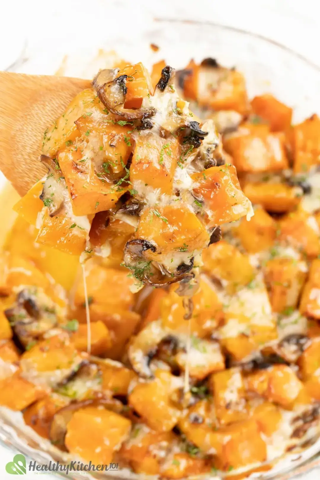 A piece of butternut squash casserole spooned up by a wooden spoon