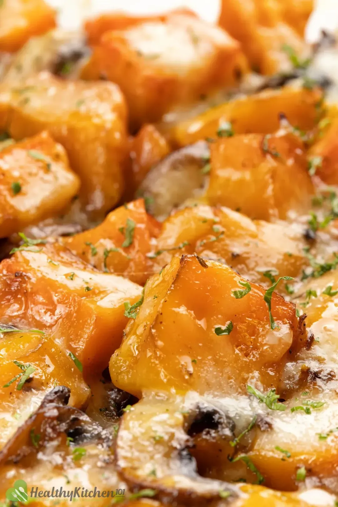 A close-up shot of butternut squash casserole with crispy edges and freckled with parsley specks