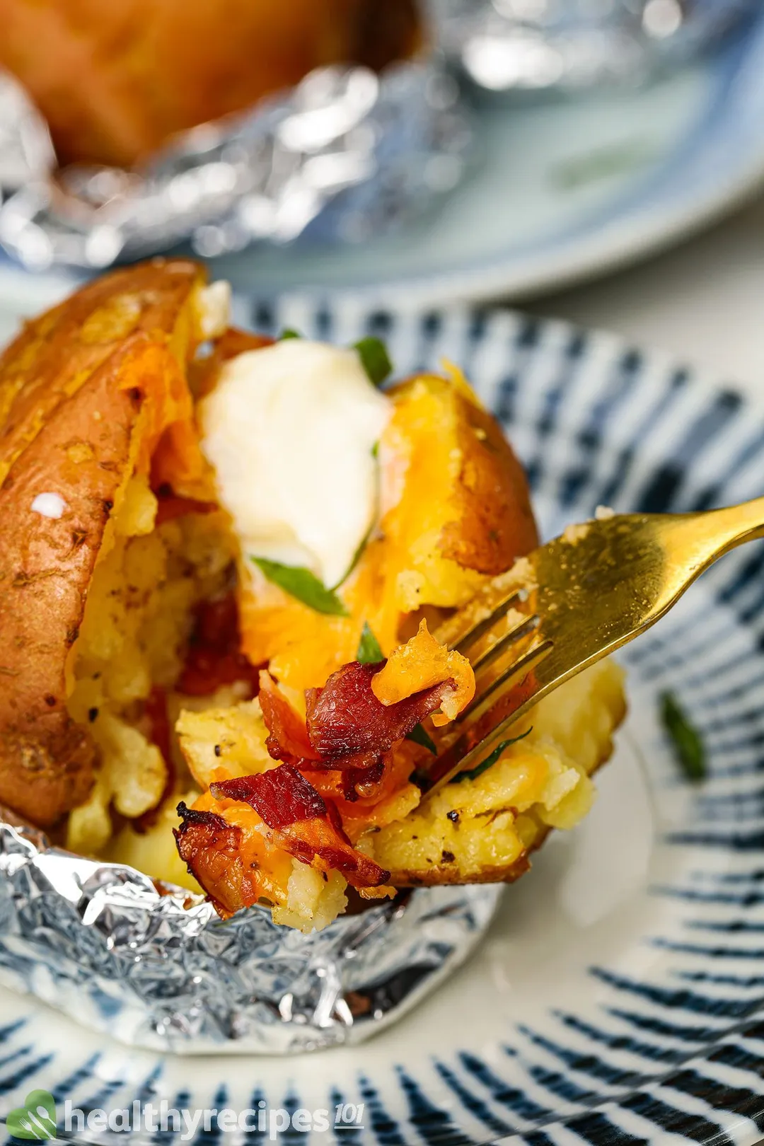 a plate of baked potato with bacon, cheese and yogurt