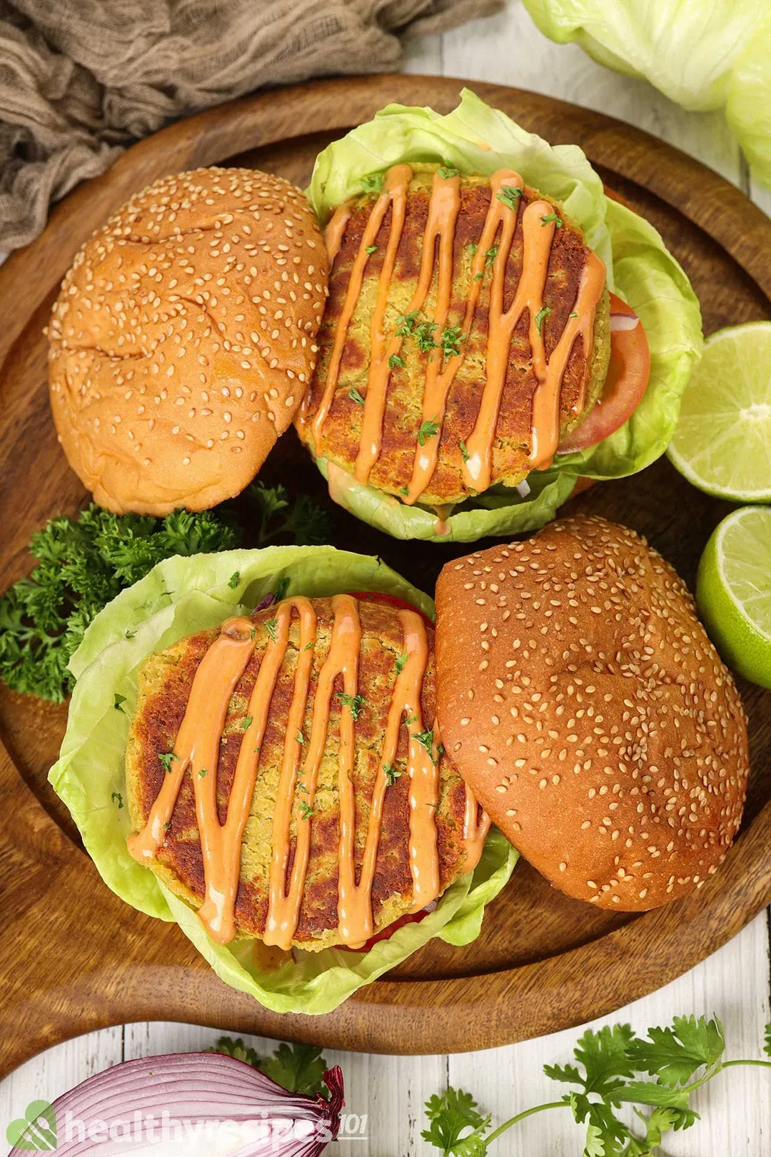 Two chickpea burgers laid on a wooden pizza board.