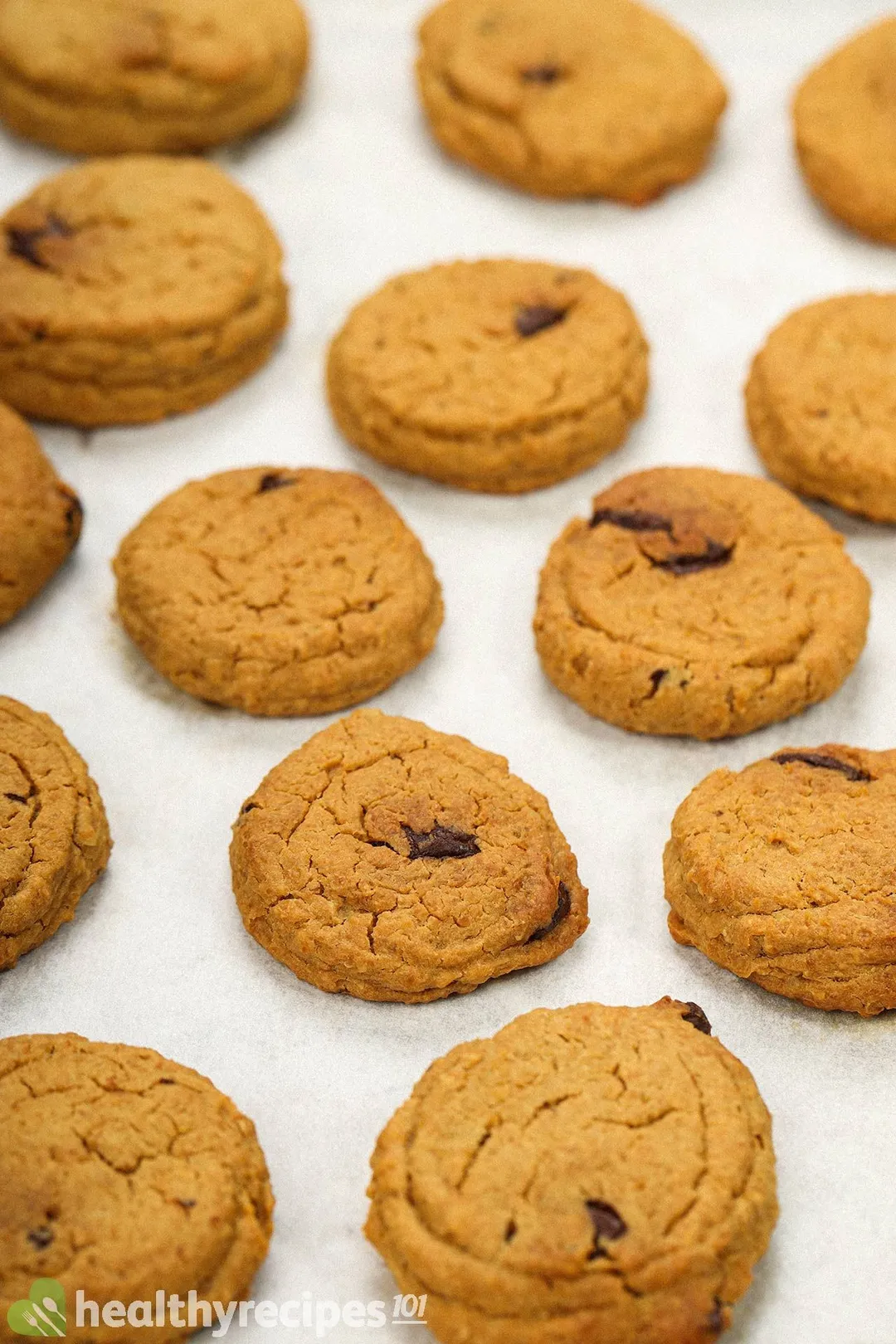 Freshly baked cookies laid on a sheet pan lined with parchment paper.