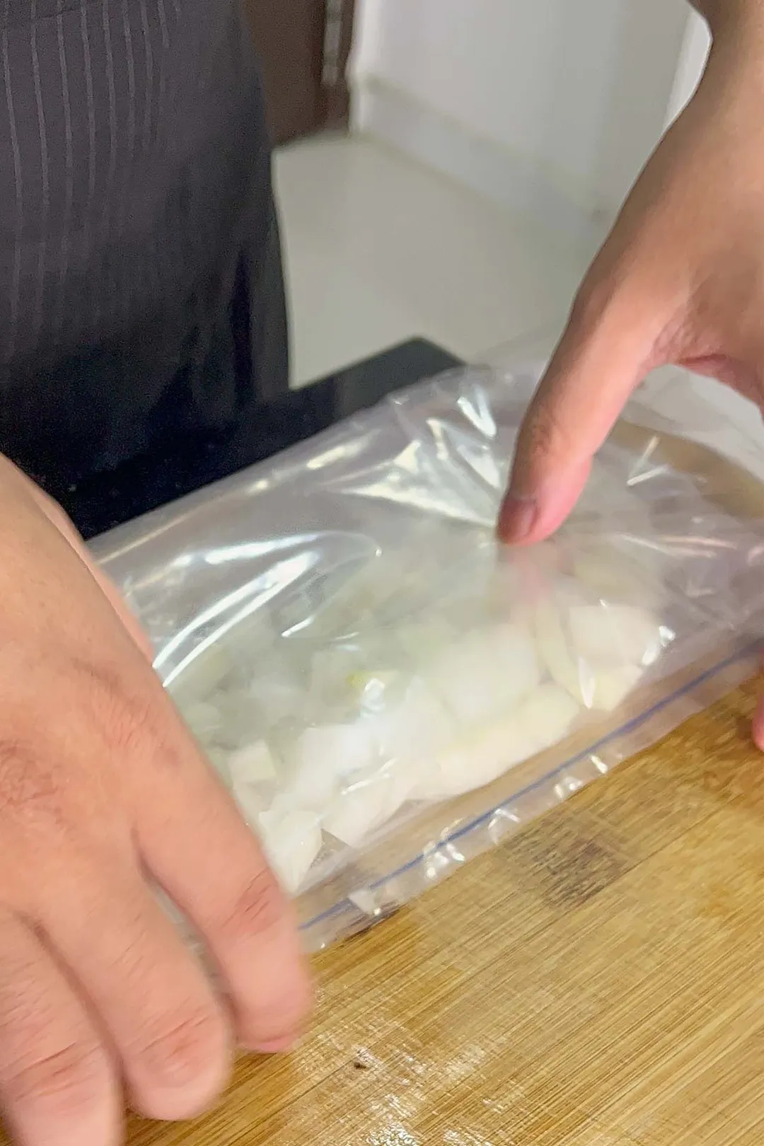 two hand holding a bag of chopped onion