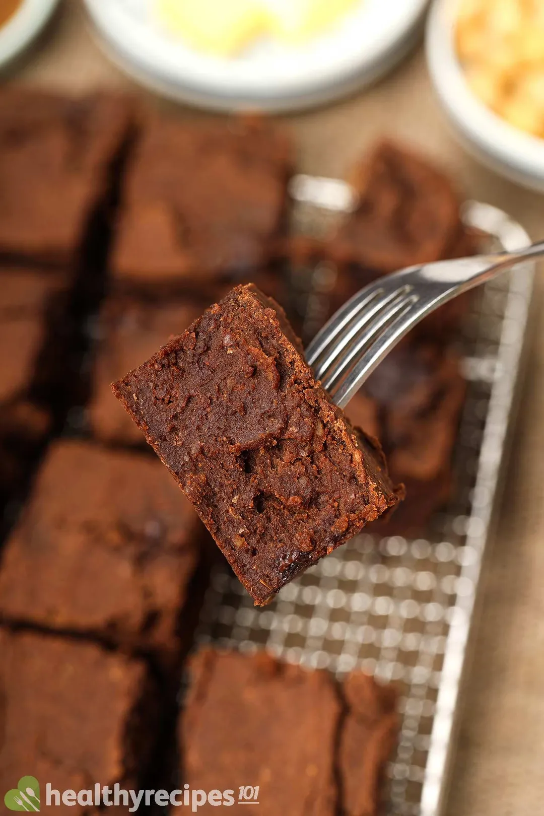 A fork piercing into a chickpea brownie squares with similar chickpea brownie squares in the background.