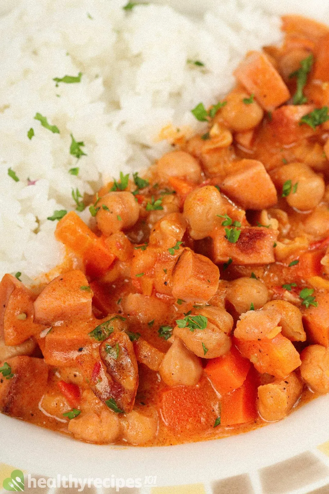 A close-up shot on a plate of food filled with chickpea stew and white rice.