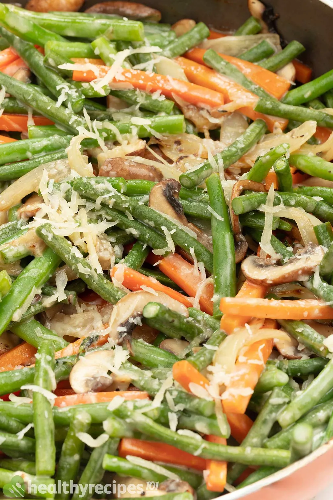A close-up shot of sauteed green beans, julienned carrots.