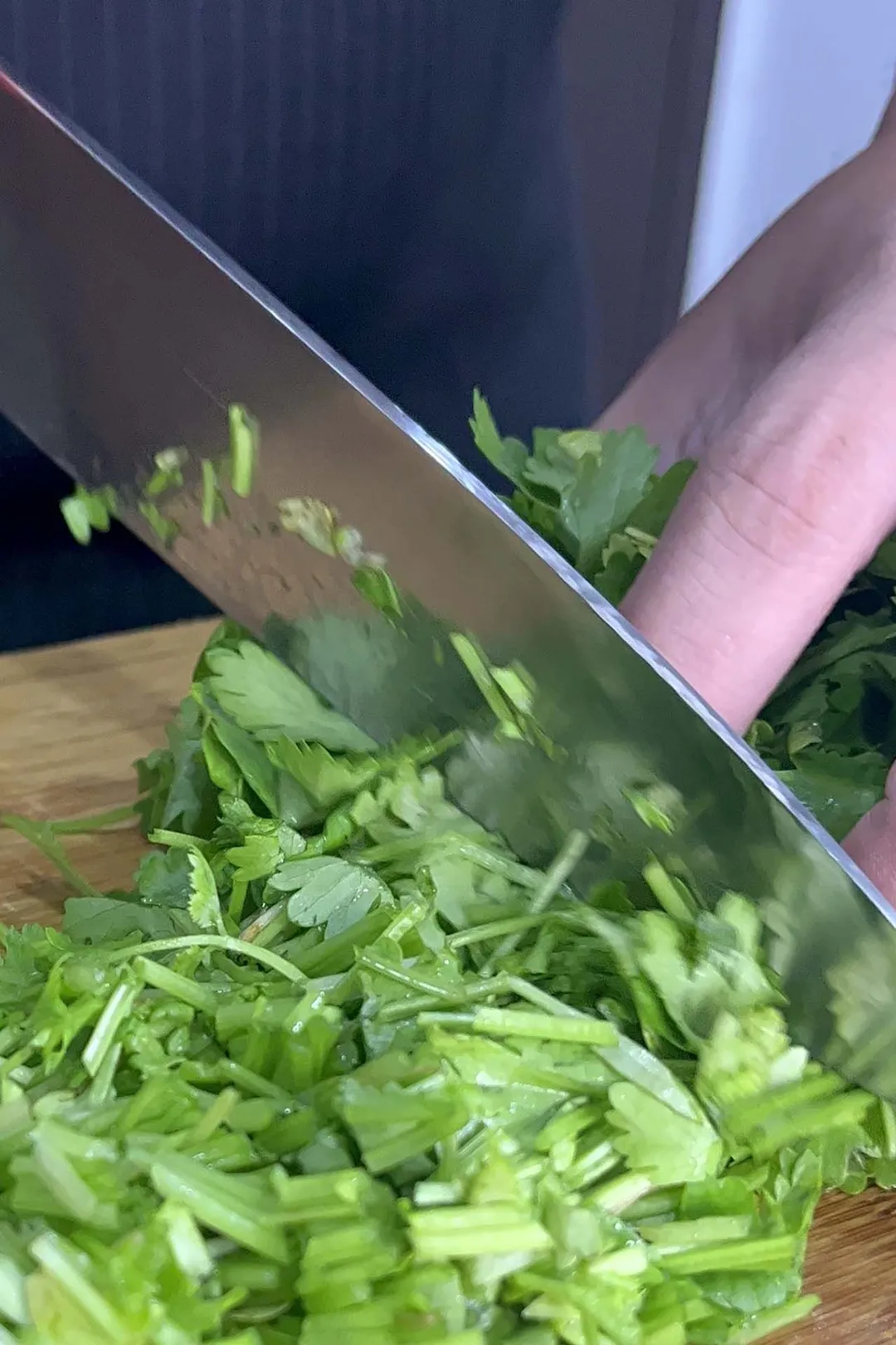 a knife cutting cilantro on a cutting board