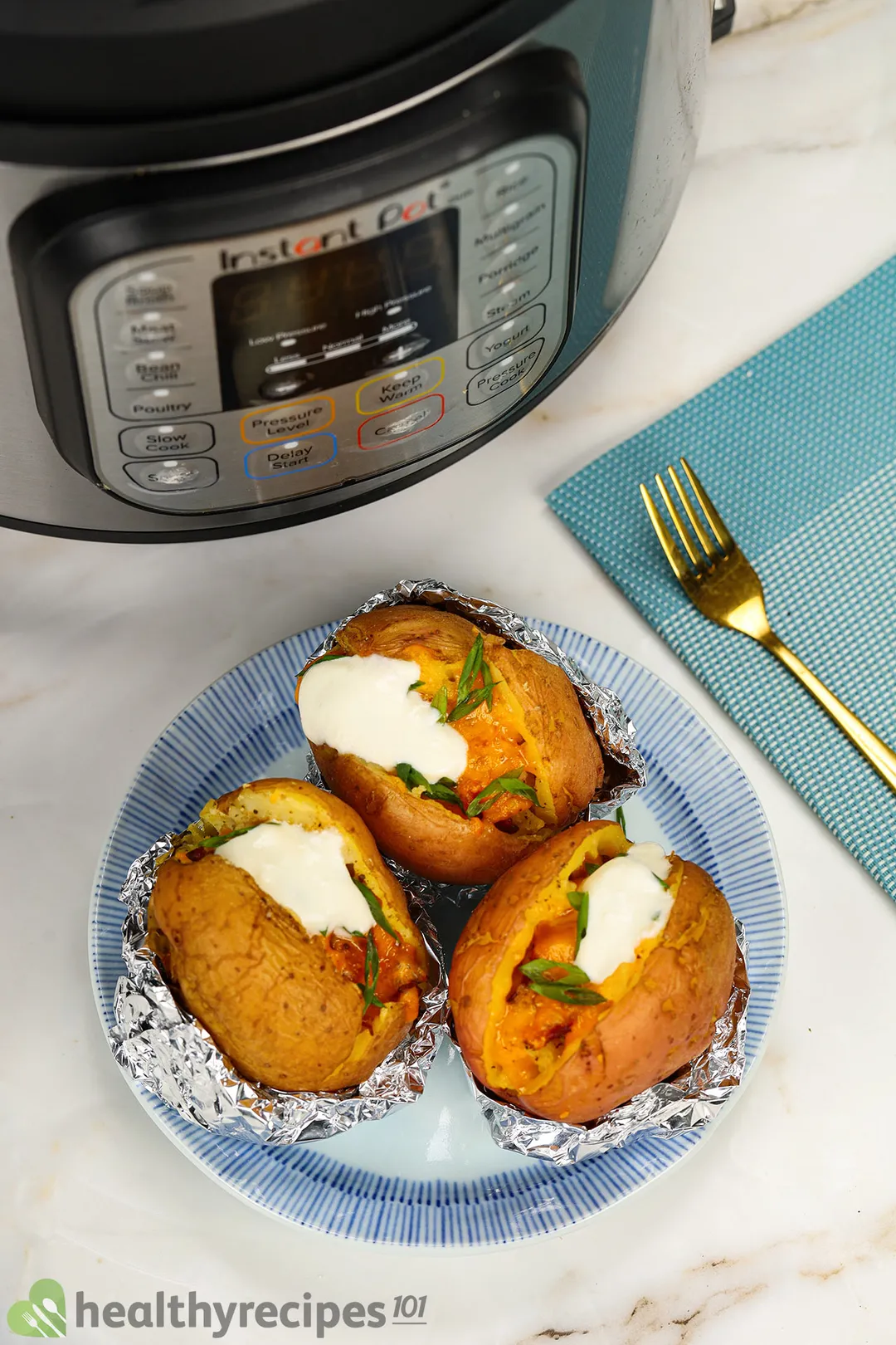 three baked potatoes on a plate next to an instant pot