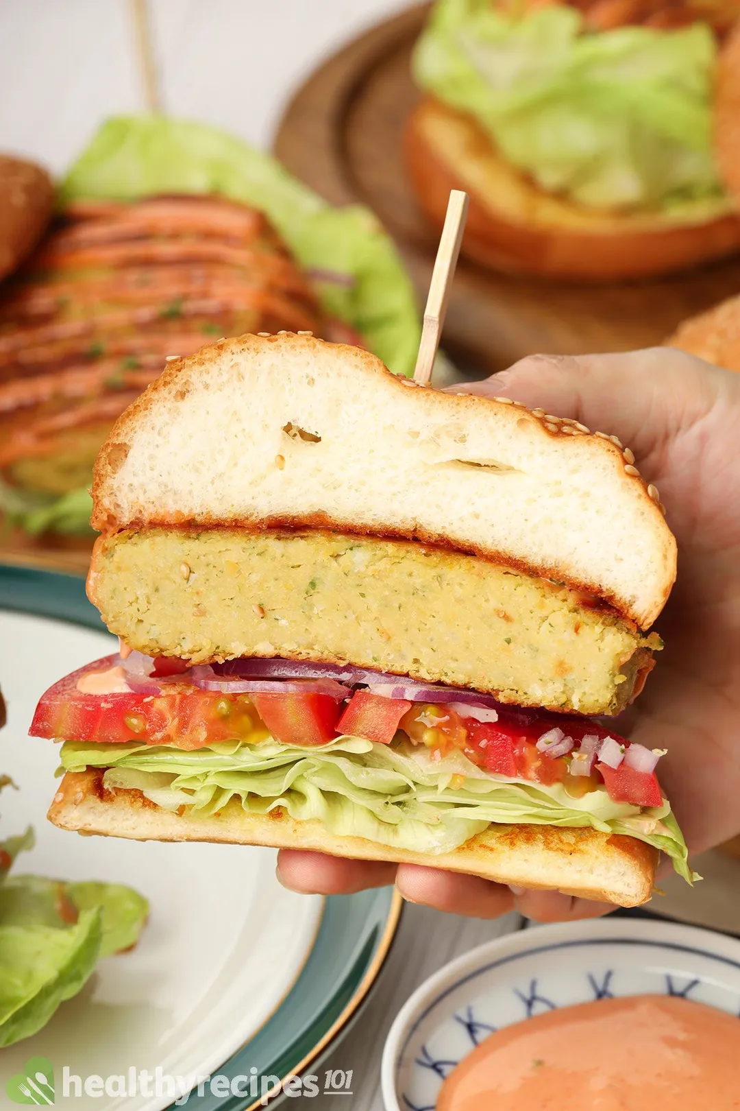 A hand holding up a chickpea burger that's been sliced in half.