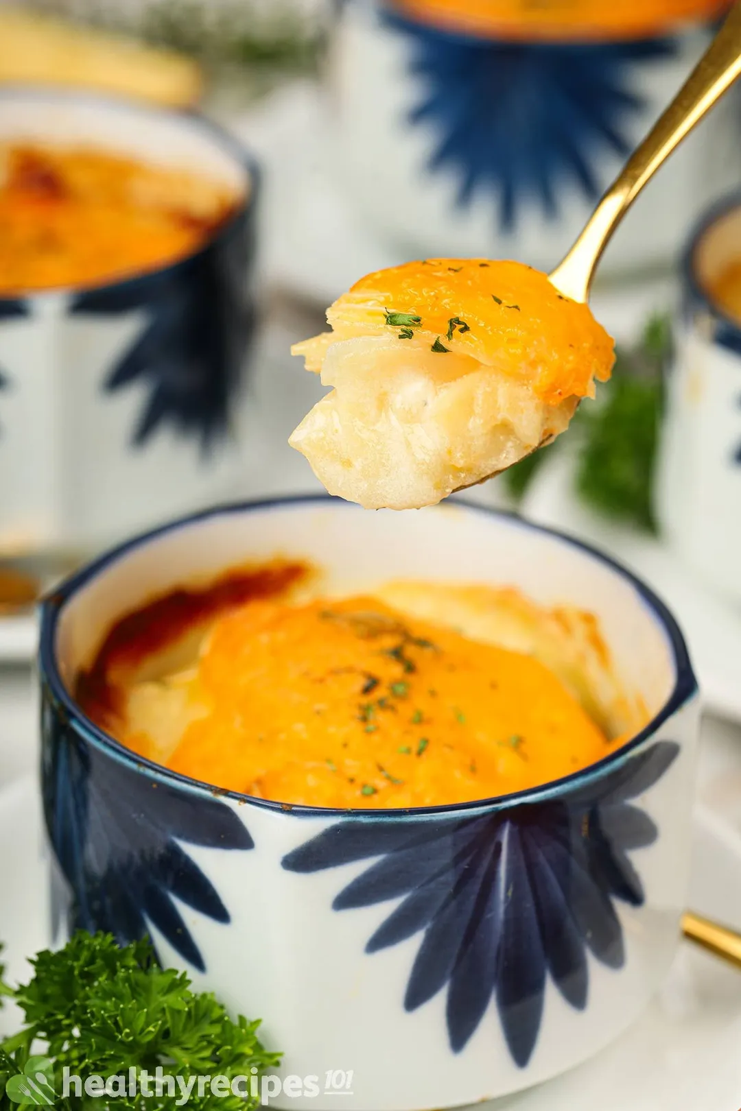 A spoon scooping up potato gratin from a bowl.