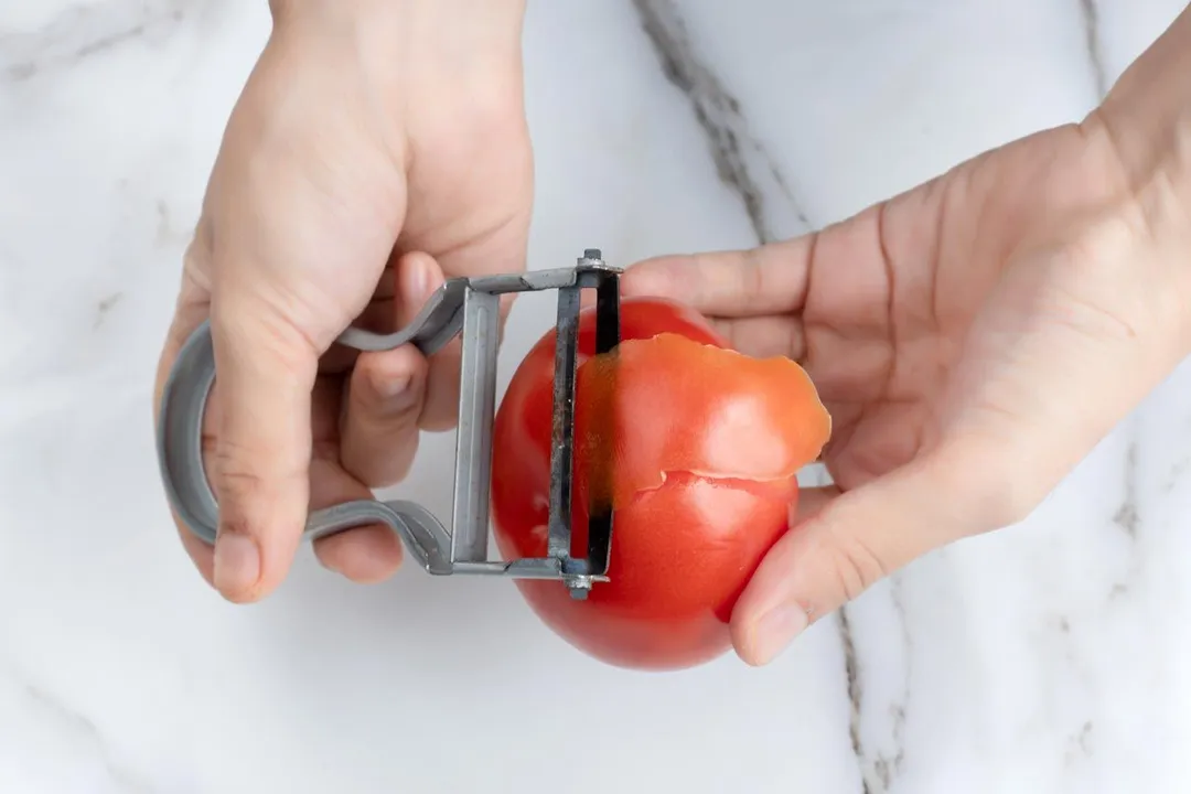 hand holding a tomato to peel