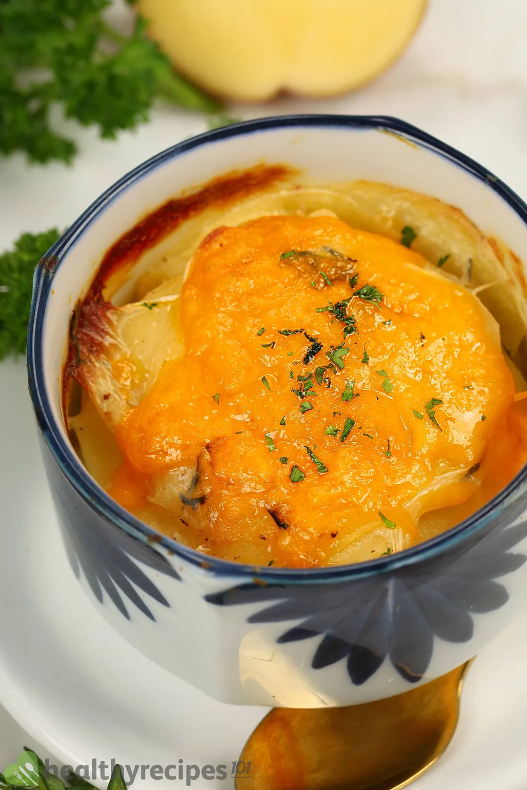 A bowl of potato gratin sprinkled with chopped parsley.