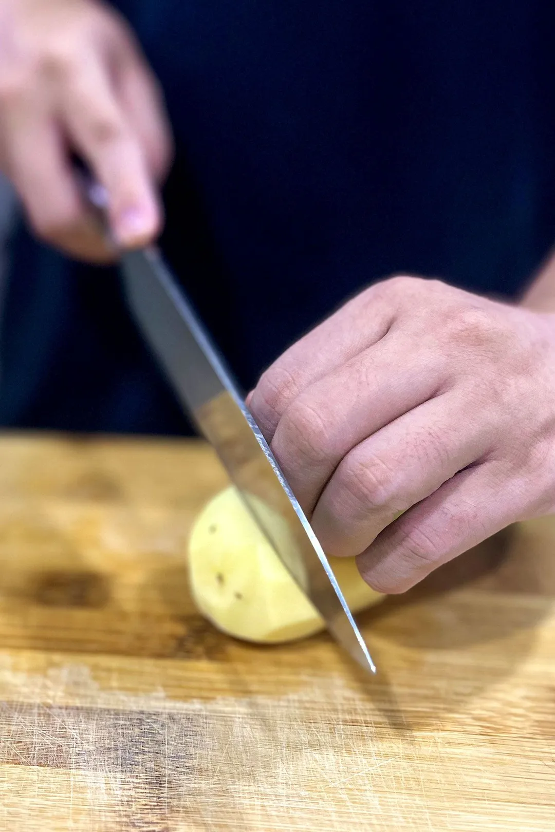 Hold a potato in one hand and use a knife to cut the potato in the other