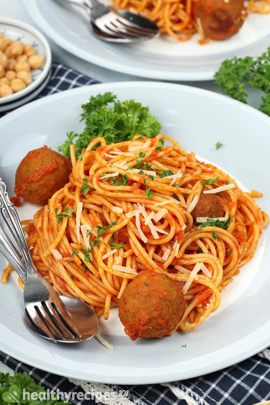 A plate of chickpea meatball spaghetti with a spoon and a fork on the side.