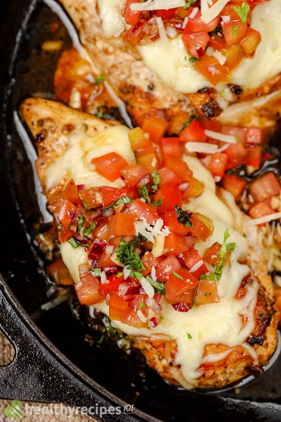 close-up shot of chicken breast with cheese and tomato on it