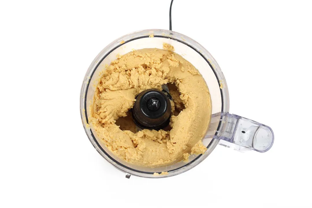 A food processor filled with chickpeas that's been blended into a creamy mash.