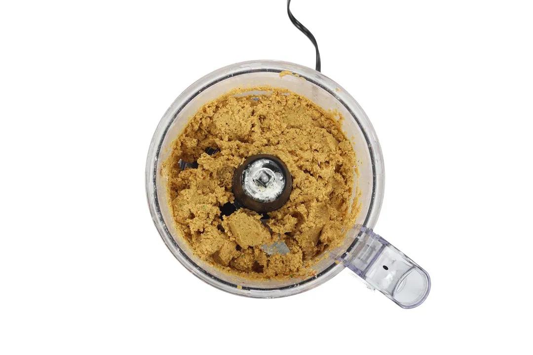 A food processor filled with chickpeas that's been blended into a creamy mash.