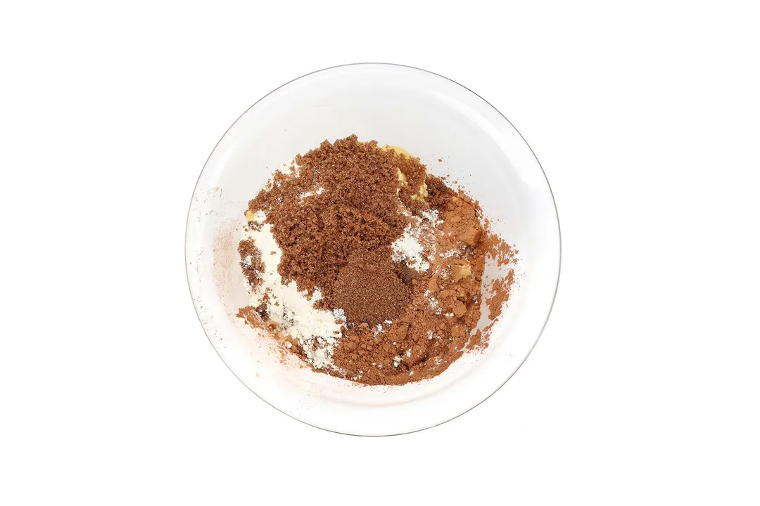 A glass bowl filled with cocoa powder, brown sugar, and all purpose flour.