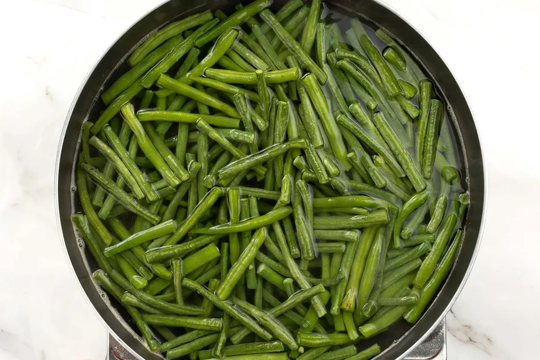 A pot cooking green beans in water.
