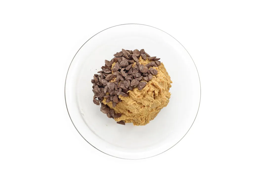 A large glass bowl containing cookie dough and chocolate chips.