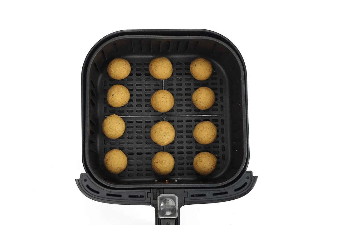 Chickpea balls laid into 3 lines in an air-fryer basket.
