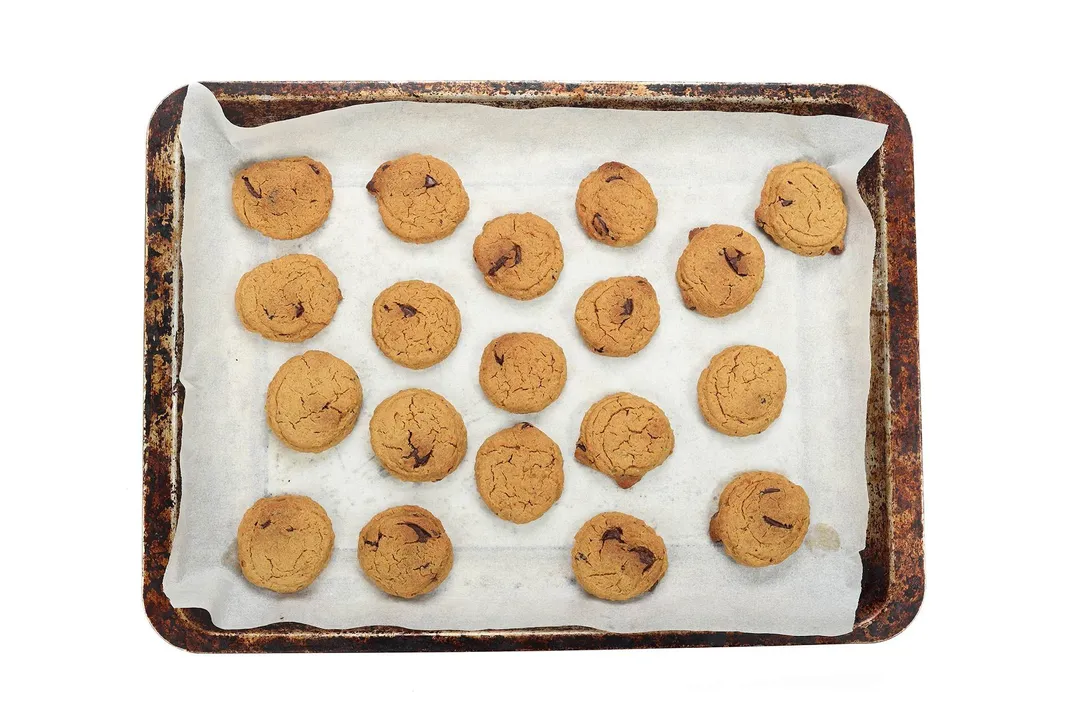 A sheetpan lined with parchment paper filled with freshly baked cookies.