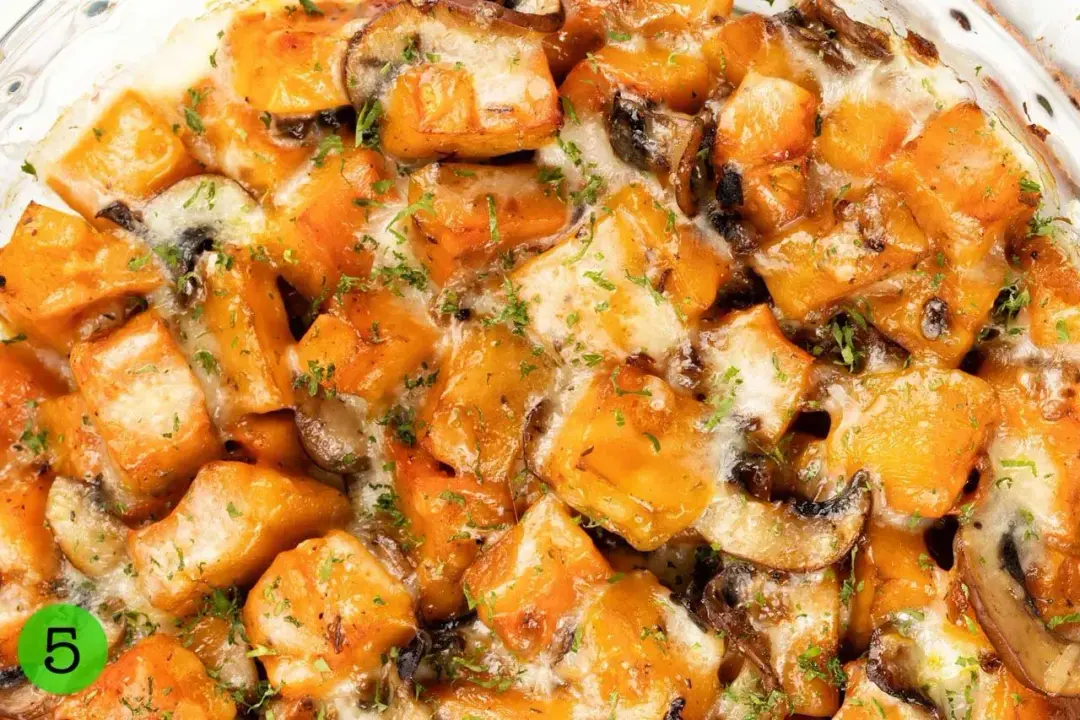 A close-up shot of baked butternut squash casserole with mushrooms and melted cheese on top