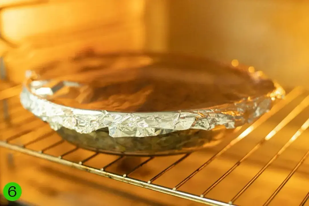 A foiled round baking dish in the heating oven