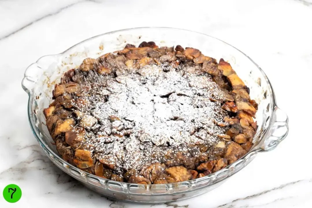 Caster sugar dusted on top of a round baking dish of French toast casserole