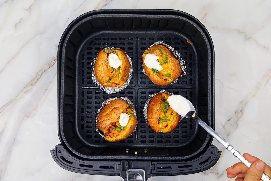 top yogurt on top of potatoes in an air fryer basket