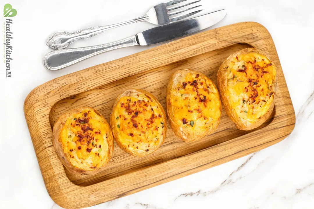 four baked potatoes on a wooden tray
