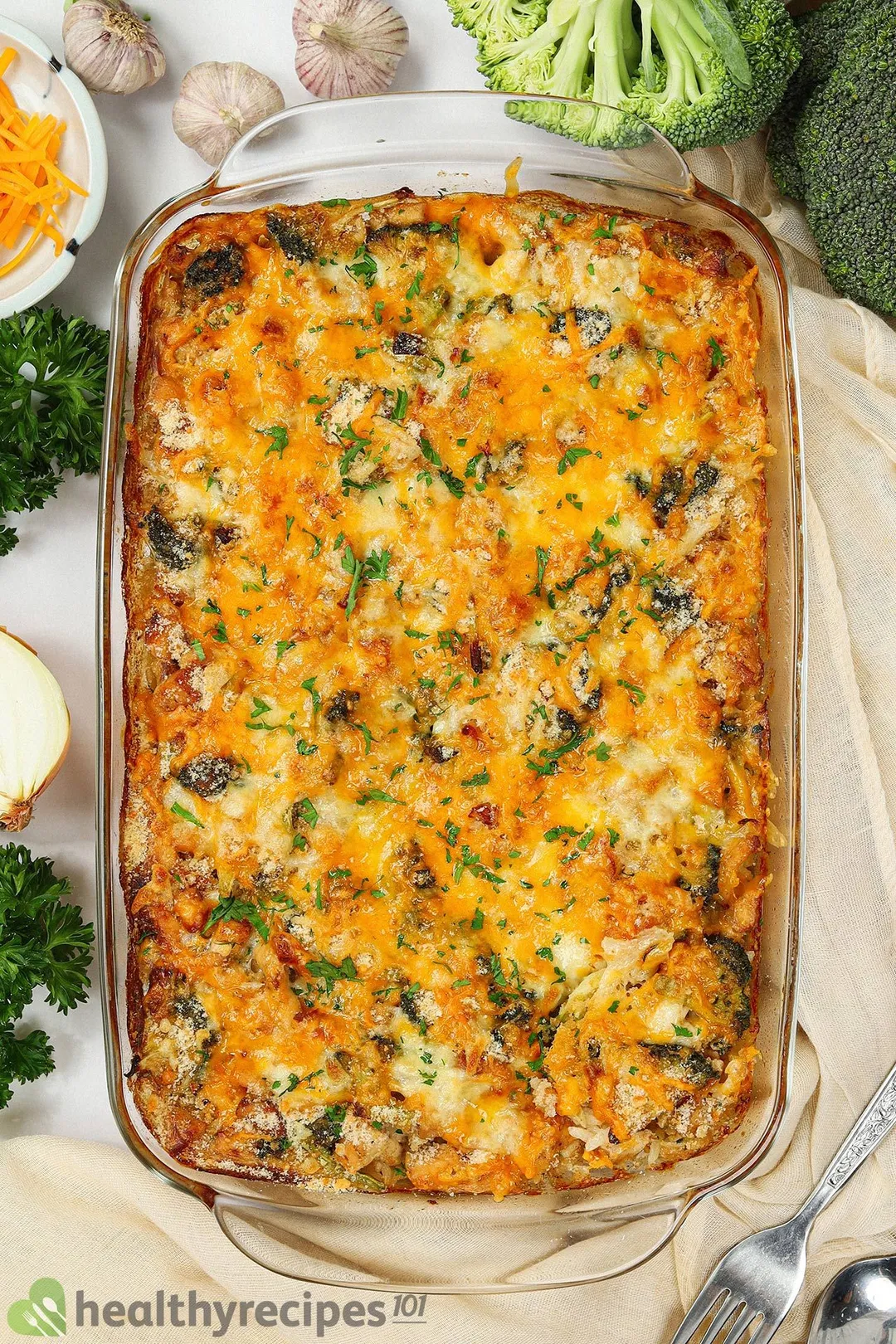 A rectangular casserole dish filled with a colorful array of fresh veggies topped with melted cheese and herbs