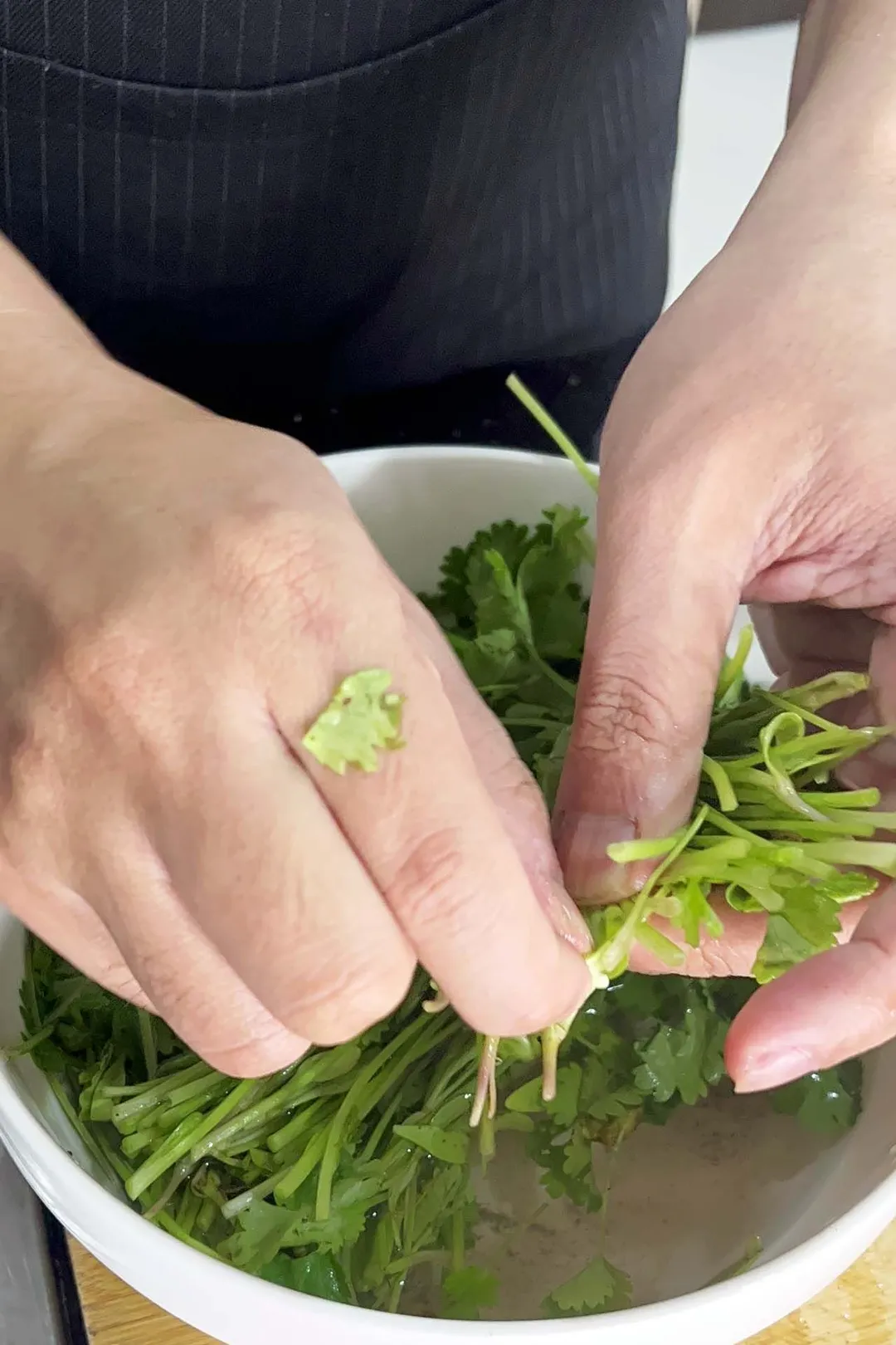washing cilantro in a large bowl by hand